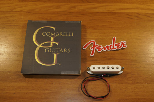 Fender Gombrelli humbucker guitar pickup with black and red wires, shown next to its original Gombrelli Guitars box and a red Fender logo decal on a white fabric background.
