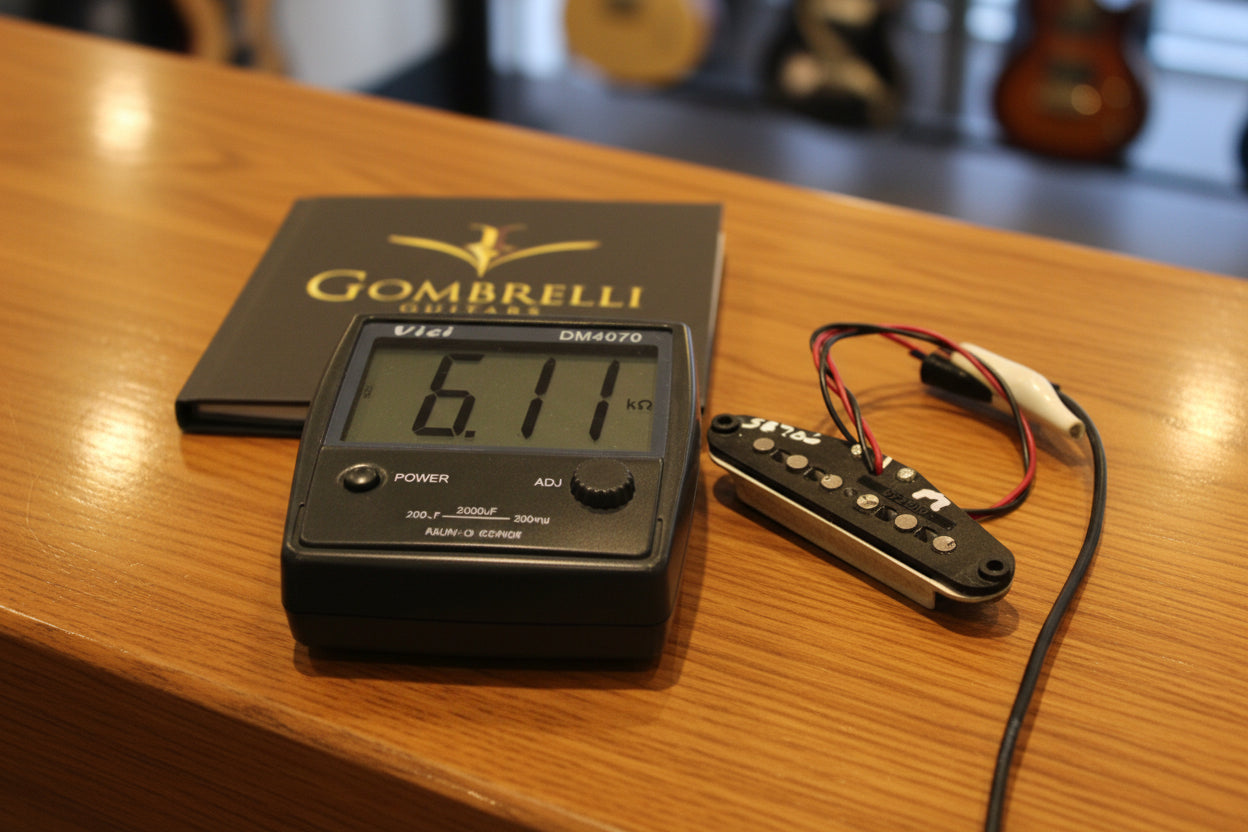 A Fender humbucker guitar pickup shown next to a Vici multimeter displaying 6.11 kOhms, with a black Fender box in the background.