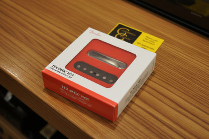 Fender Tex-Mex Hot Telecaster Pickup Set in its original white and red retail box, featuring a window showing the red and brown pickups, with a gold G&G sticker on a black textured background.