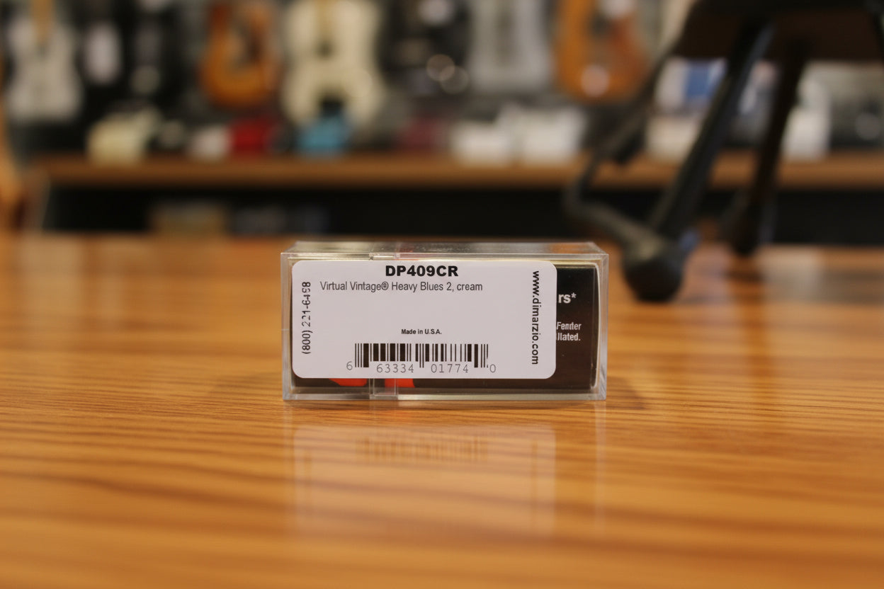 A close-up of a clear plastic case containing a vintage DPM (Double Precision Metal) slot coin, specifically DP409CR Virtual Vintage Heavy Blues 2, cream. The label is white with black text and a barcode, and the coin itself is partially visible through the clear casing.