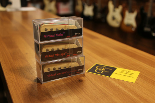 Three custom selected Dimarzio Virtual Vintage guitar pickups stacked vertically on a shiny satin fabric, with a yellow and black Gombrelli Guitars card on the right.